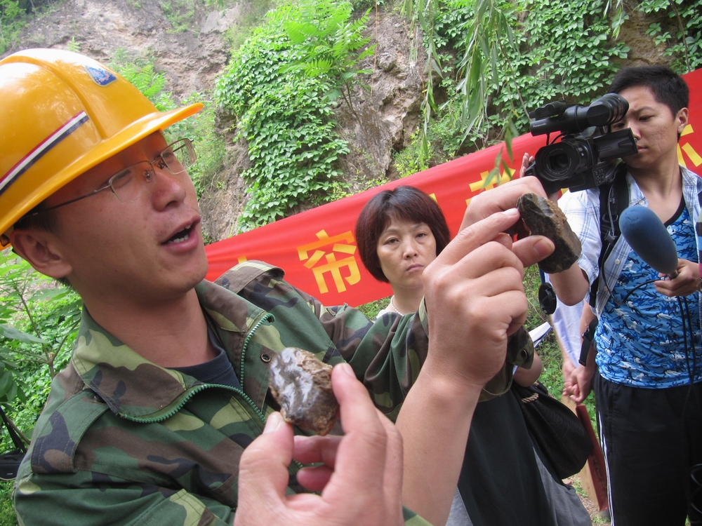 水帘洞考古人员向参观者展示出土石器.JPG